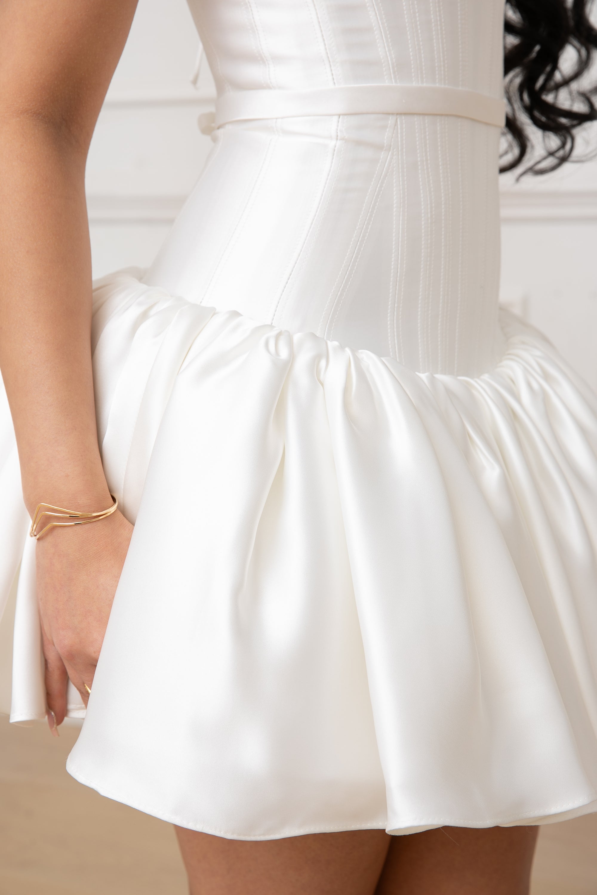 The Duchess Dress by Brunell by Shar, white satin mini dress, close-up of the defined waist, dainty belt, flared gathered drop-waist ultra mini skirt, and feminine silhouette.