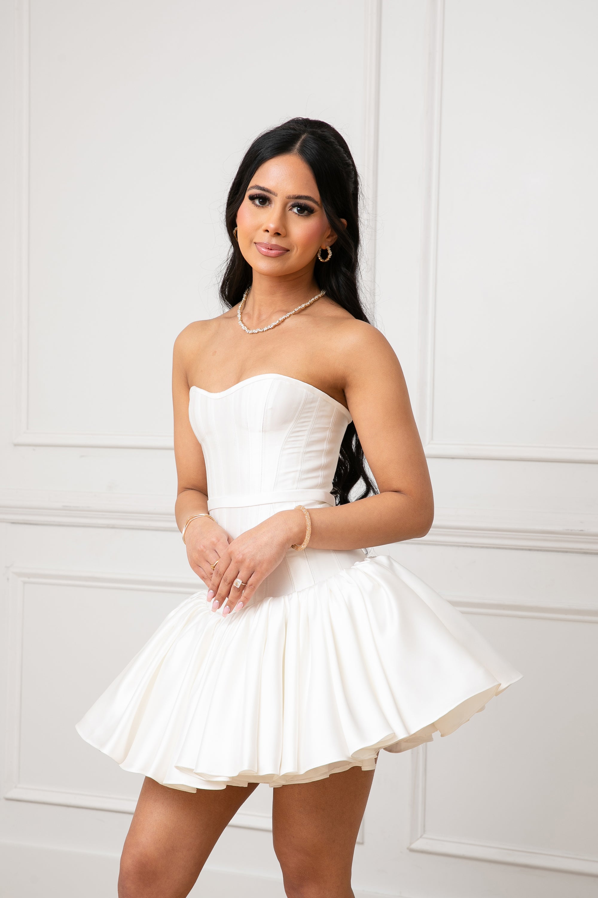 Close up view of the Duchess Dress by Brunell by Shar, white satin strapless mini dress, featuring a sweetheart neckline, drop waist bodice and flared gathered ultra mini skirt.